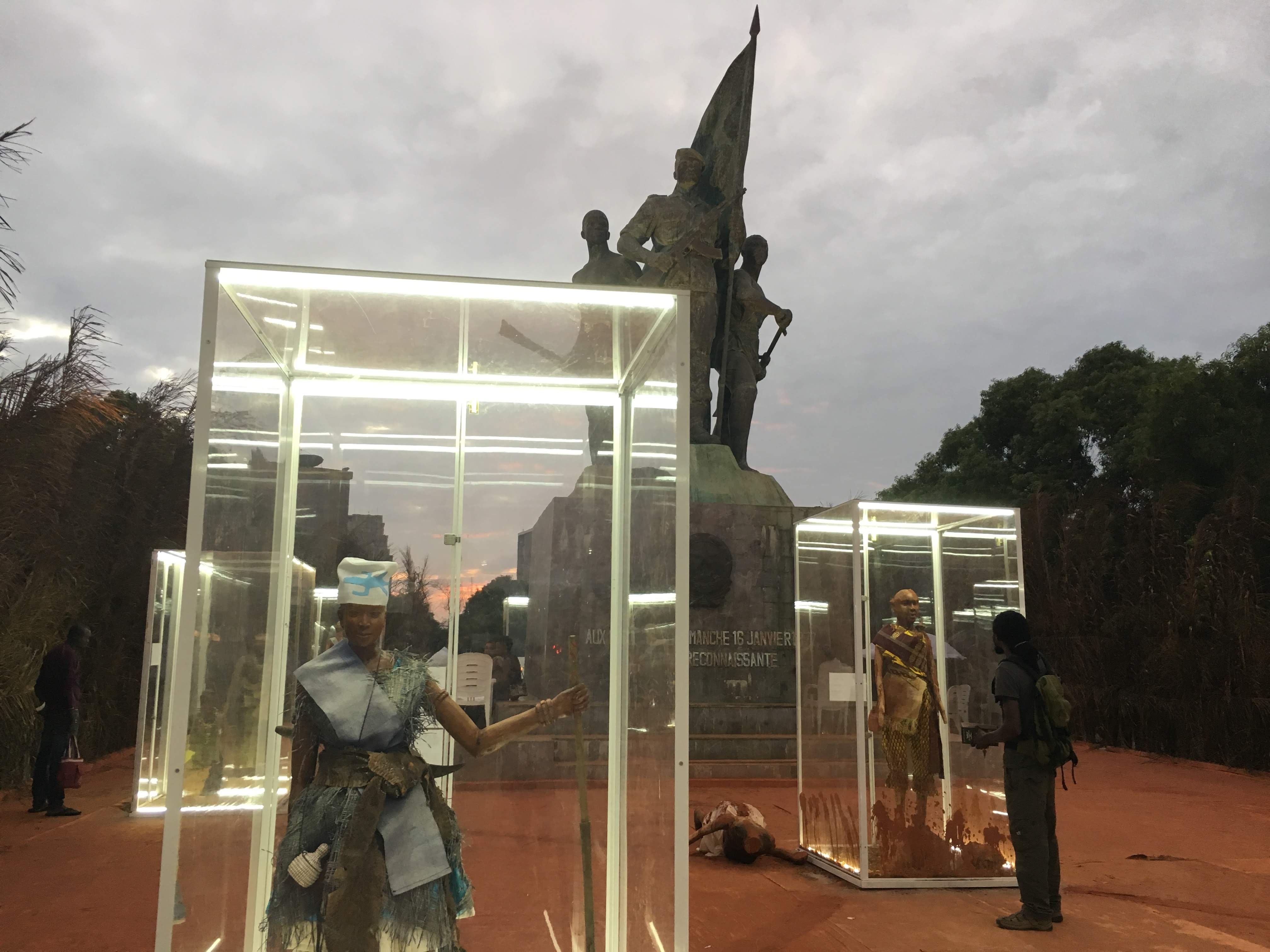 Cages en verre disposées autour de la statue centrale de la place du Souvenir et constituant une partie de l’exposition « Minɔ : Amazones du Dahomey », Cotonou, 1er août 2018, Mihena Maamouri