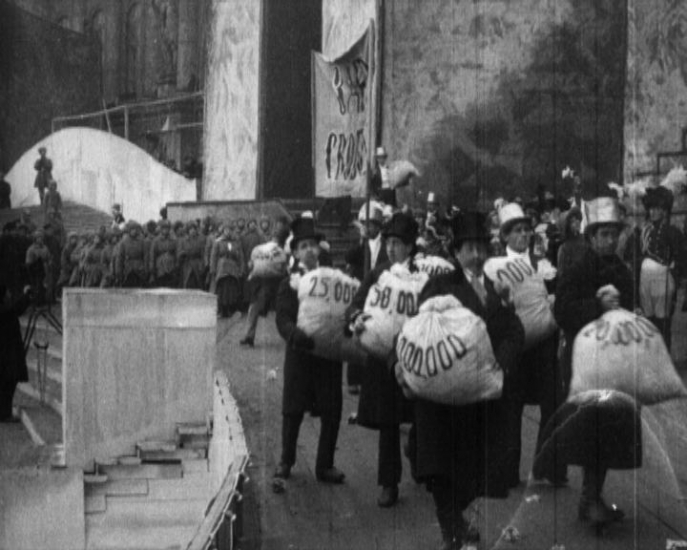 Représentation satirique des banquiers volant l’argent recueilli lors du grand emprunt levé pour financer la guerre, dans une scène du spectacle d’Evreinov, La Prise du Palais d’hiver, Petrograd, 7 novembre 1920. Représentation satirique des banquiers volant l’argent recueilli lors du grand emprunt levé pour financer la guerre, dans une scène du spectacle d’Evreinov, La Prise du Palais d’hiver, Petrograd, 7 novembre 1920.