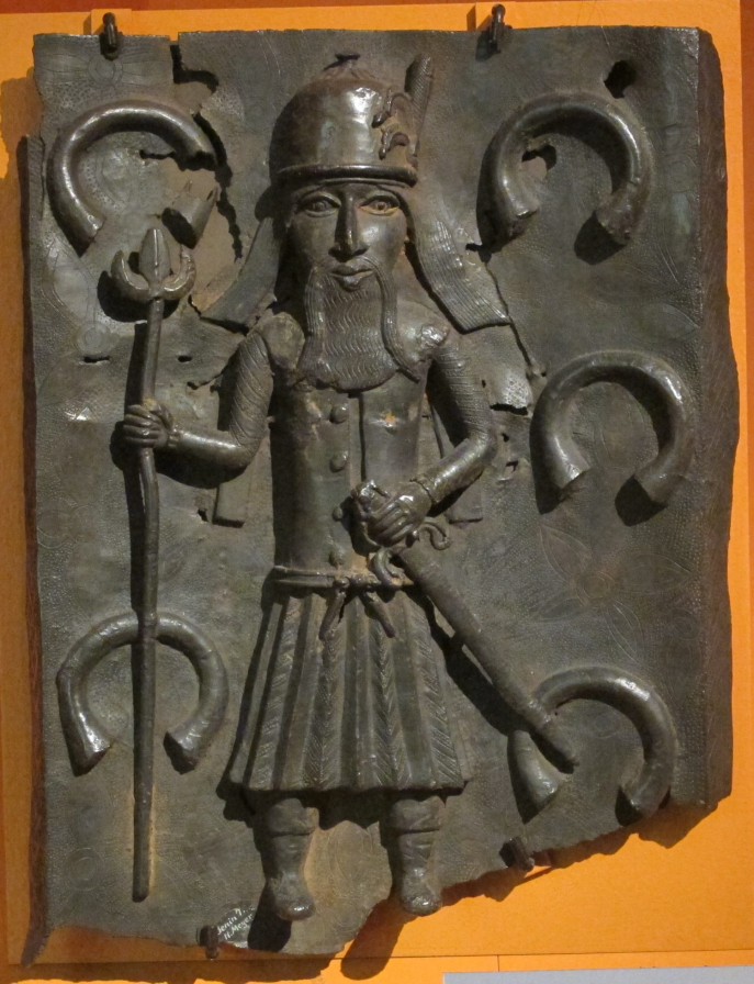 A 16th-century Benin Bronze depicting a Portuguese soldier, with manilhas in the background. Wkisource